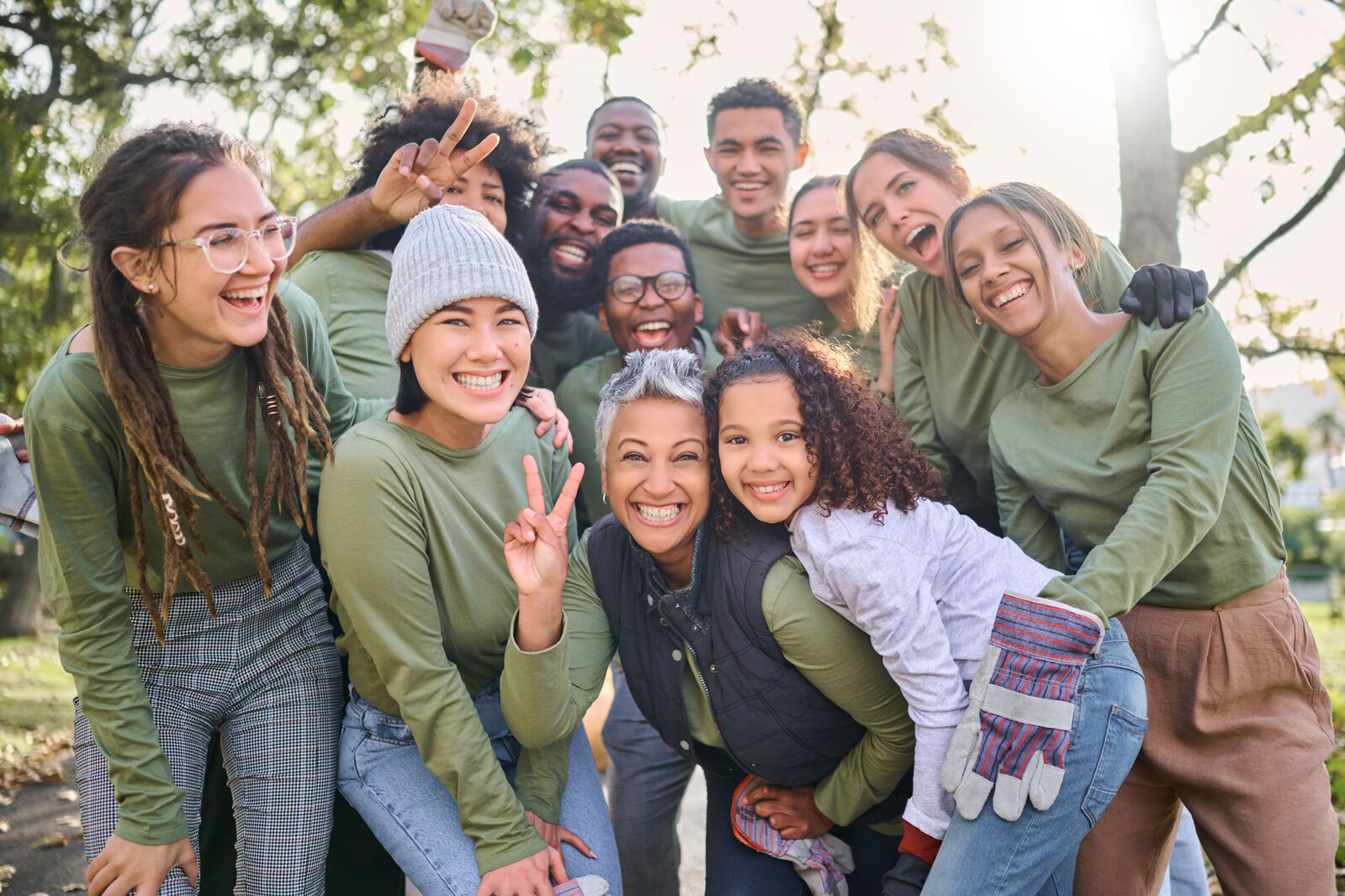 A group of young people smiling and posing together for a photo in a sunny park setting.
